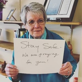 woman holding up sign with stay safe message