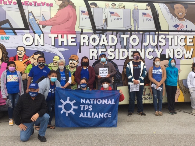 group in front of bus holding national tps alliance flag